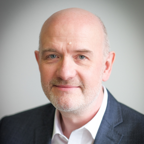 Photograph of Dr Chris Jones, CTO of 365 Response. Chris wears a formal suit jacket and a white shirt, with an open collar and no ties. Chris has a reassuring smile.